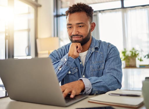 A male person of color working in front of his laptop.