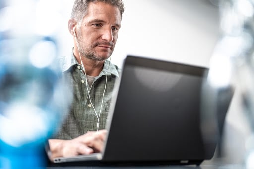 A man in earphones working in front of his laptop.