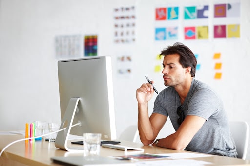 A man working seriously at his Apple computer on his desk