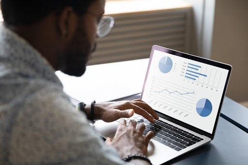 A businessman, using his laptop, is analyzing the TACoS Amazon through a graph.